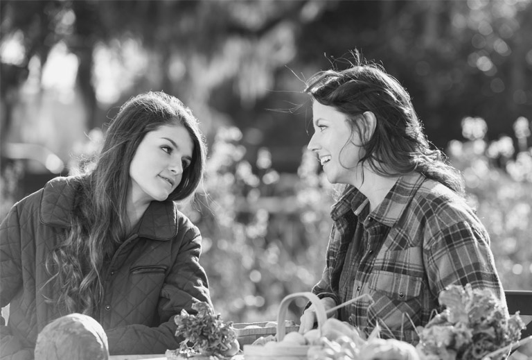 Black and white photo of a teen girl and older woman talking at a picnic