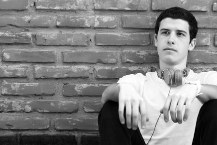 Black and white photo of a young man with earphones around his neck